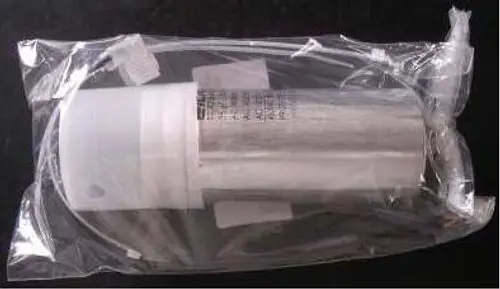Kondensator in transparentem Verpackungsmaterial; die Marke Remeha ist sichtbar. Der Kondensator ist aus Metall mit einem Anschlusskabel und scheint für elektrische Anwendungen verwendet zu werden.